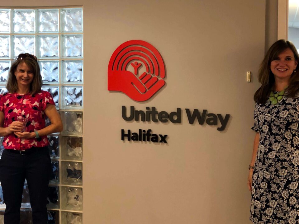 Two women standing on either side of a United Way Halifax sign