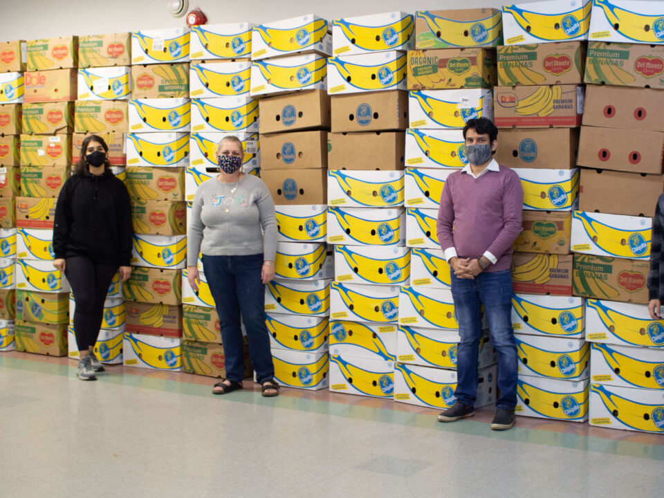 Volunteers stand in front of Christmas hampers for community