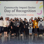 A large group of people standing in front of a sign that says Community Impact Sector Day of Recognition