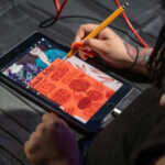Artist Bria Miller draws a live art piece on a tablet