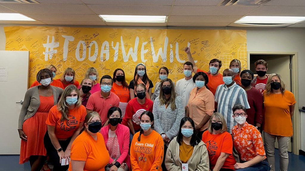 A group of United Way Halifax staff members, all wearing masks and most wearing orange shirts