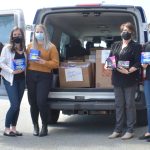 NSGEU employees standing at the back end of their branded work van, which is filled with menstrual products for Menstrual May