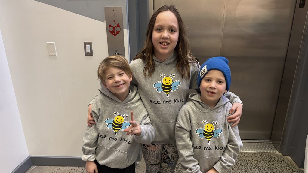 Three children wearing sweatshirts that say