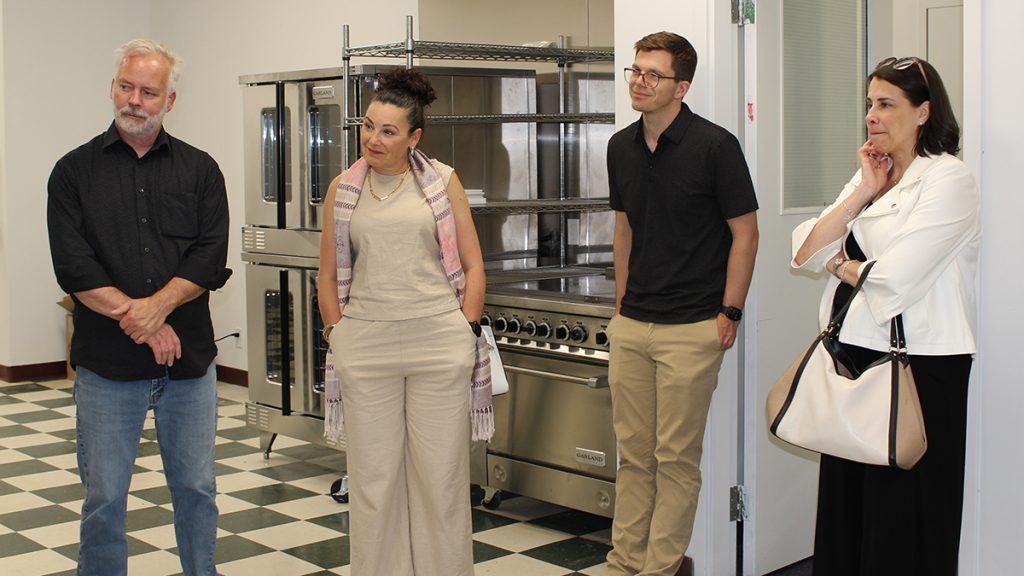 two men and two women standing in a commercial kitchen