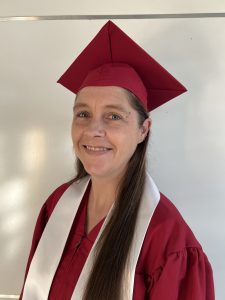 A smiling, confident woman in a graduation gown and cap