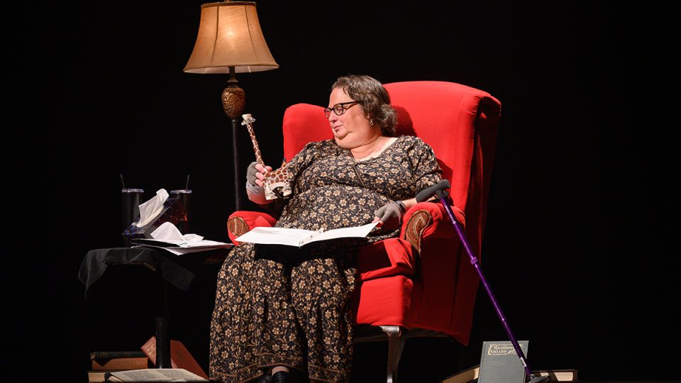 a woman sitting in a chair with a wooden giraffe