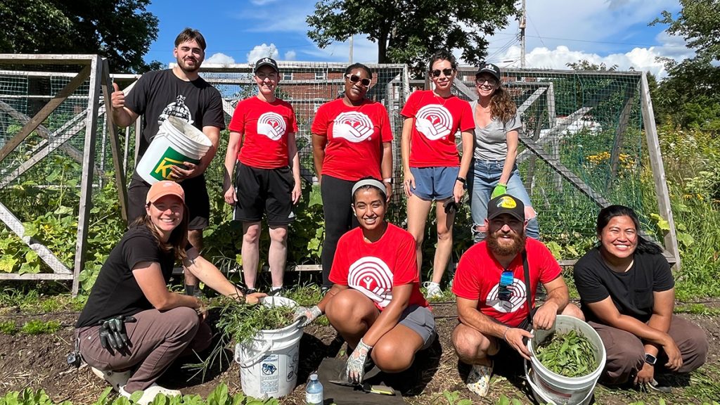 A group of people, several wearing United Way shirts, standing and crouching in a garden